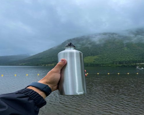 A person holding a sleek reusable metal water bottle outdoors