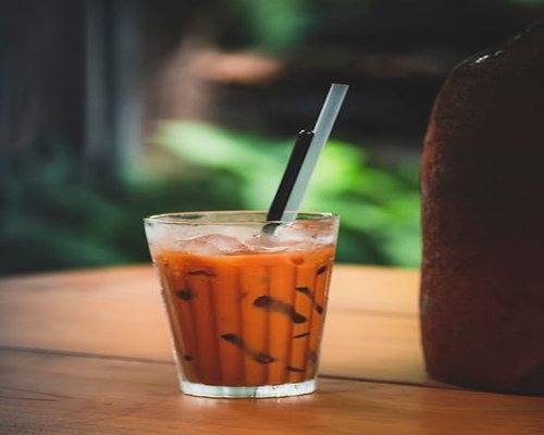A cold glass of iced Thai tea with condensation on the outside